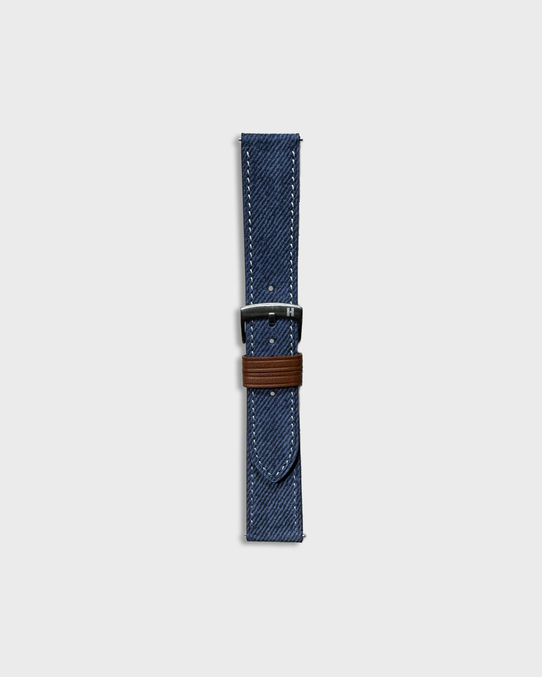 Indigo Denim__Blue denim watch strap with brown buckle on a light gray background